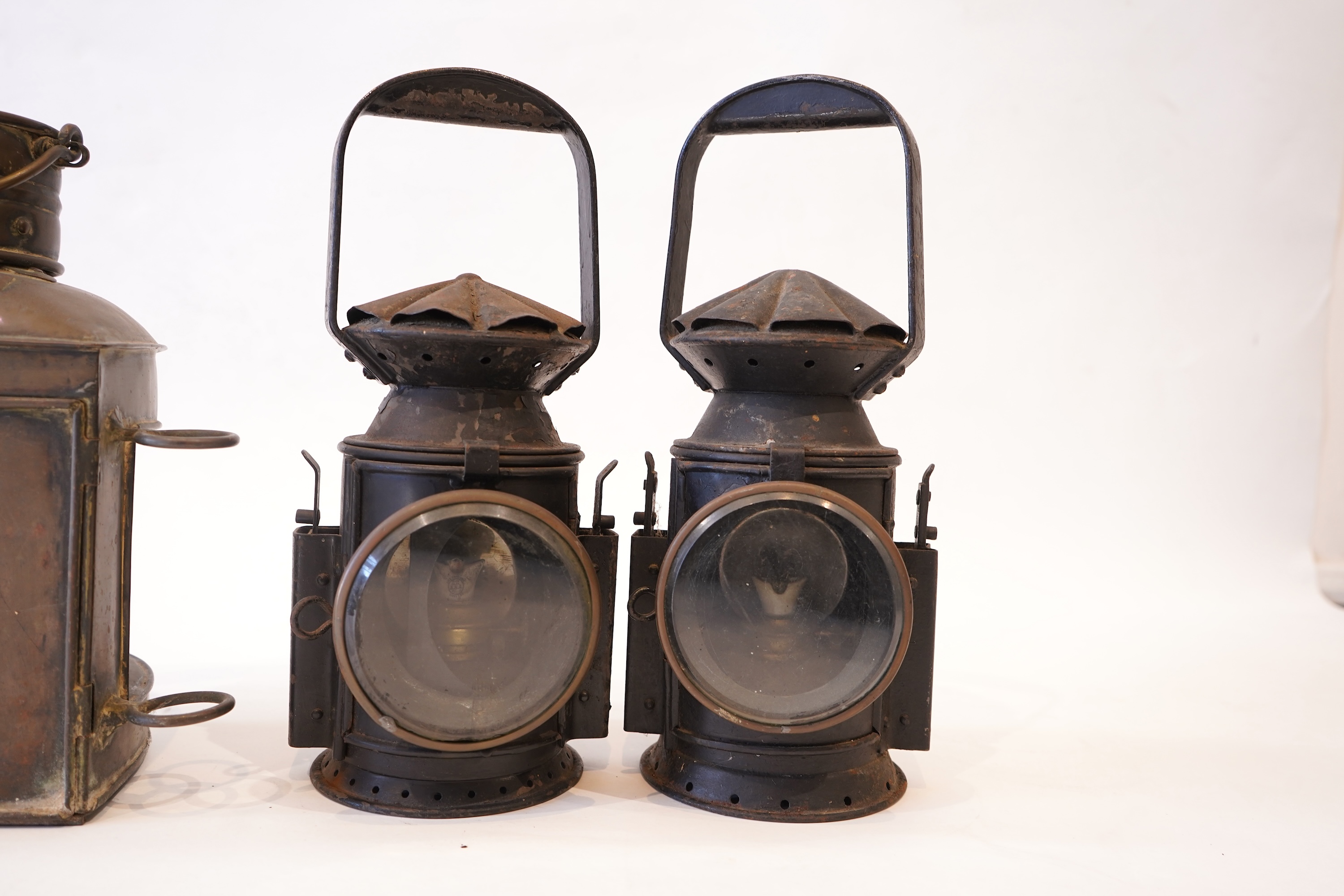 Two black painted railway hand lamps by Pratt & Co. Ltd. Birmingham, both dated 1945, both with burners and reflections, one intended for three colour aspect, with one glass missing, together with a brass ship’s bulkhead